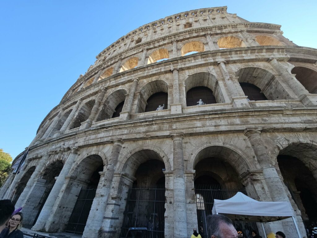 Low-angle view of the Colosseum in Rome under clear blue sky