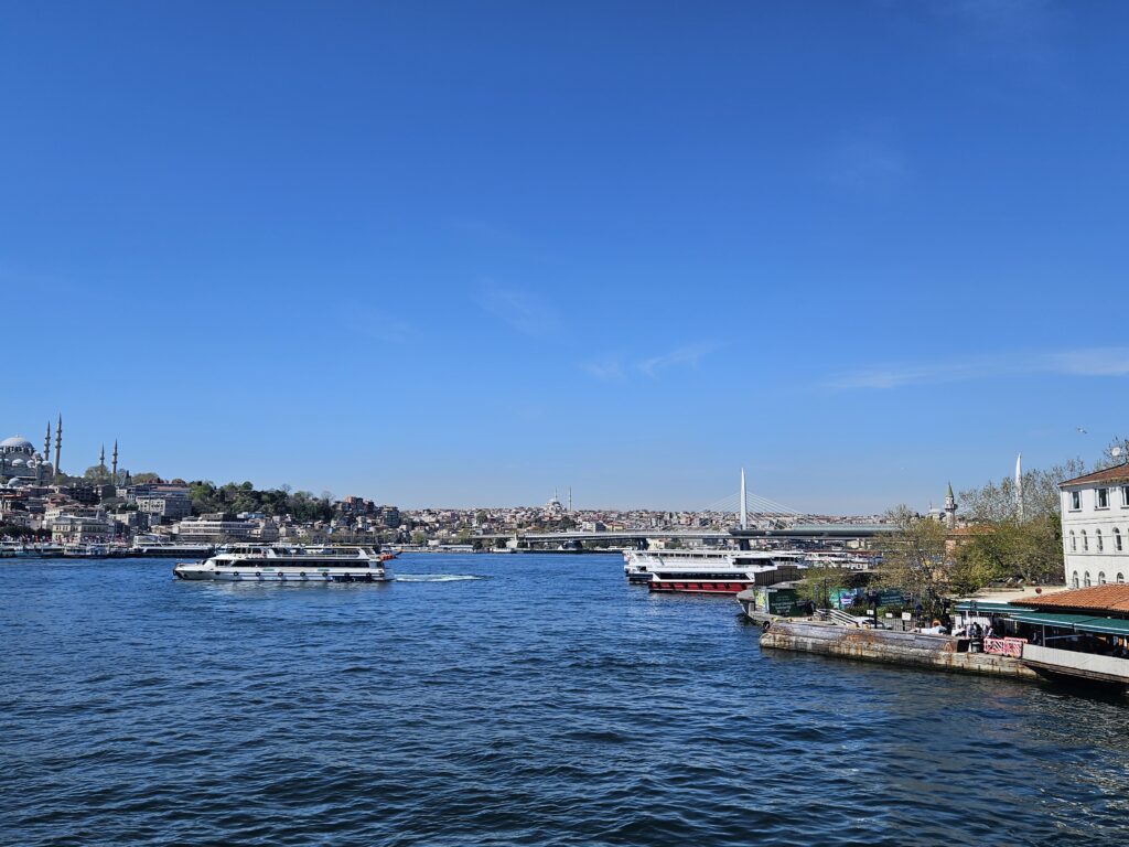 Wide view of the Bosphorus with ferries and Istanbul cityscape under blue sky.