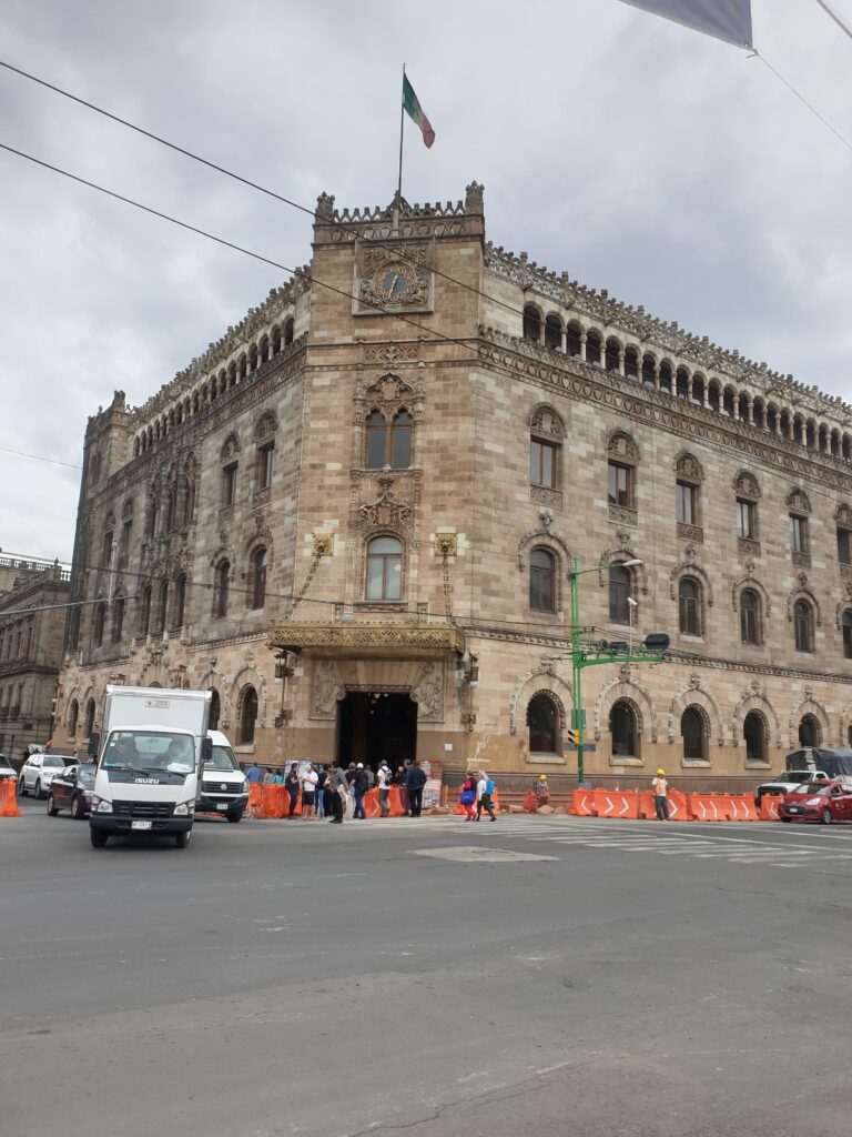 Historic building and street scene in Mexico City with people walking nearby.