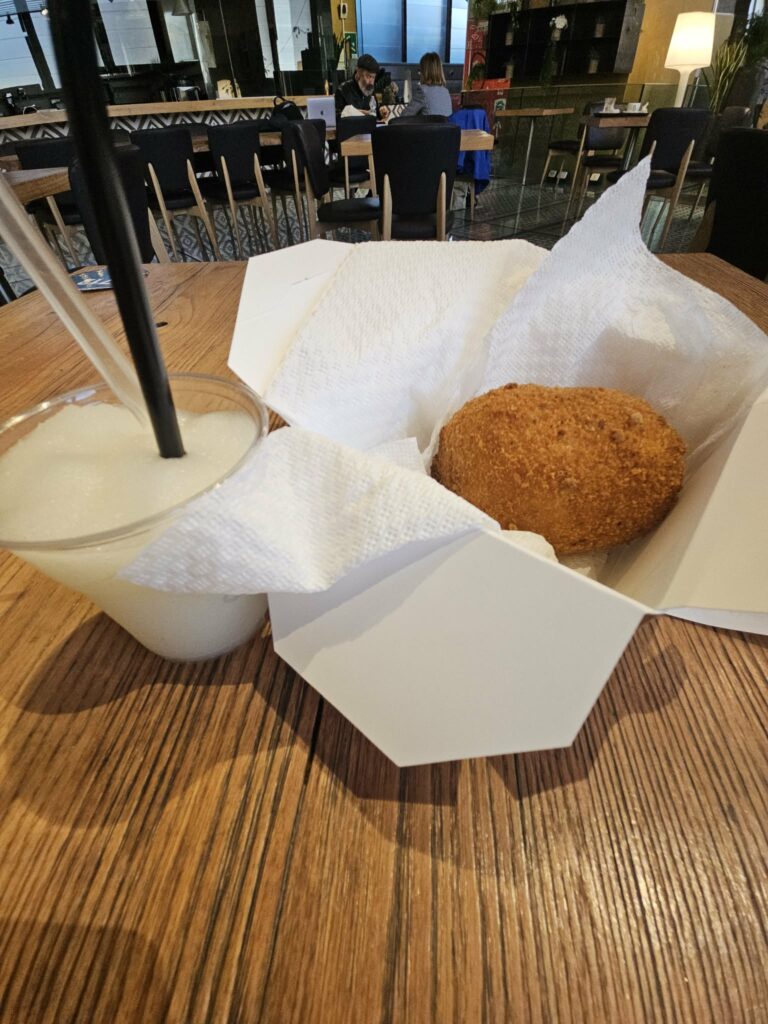 Supplì and a drink on a table in a casual Rome setting.